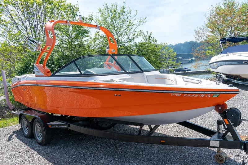 Slide: The Image of 2013 Nautique 210 SUPER AIR boat in bright orange on a trailer. - 8