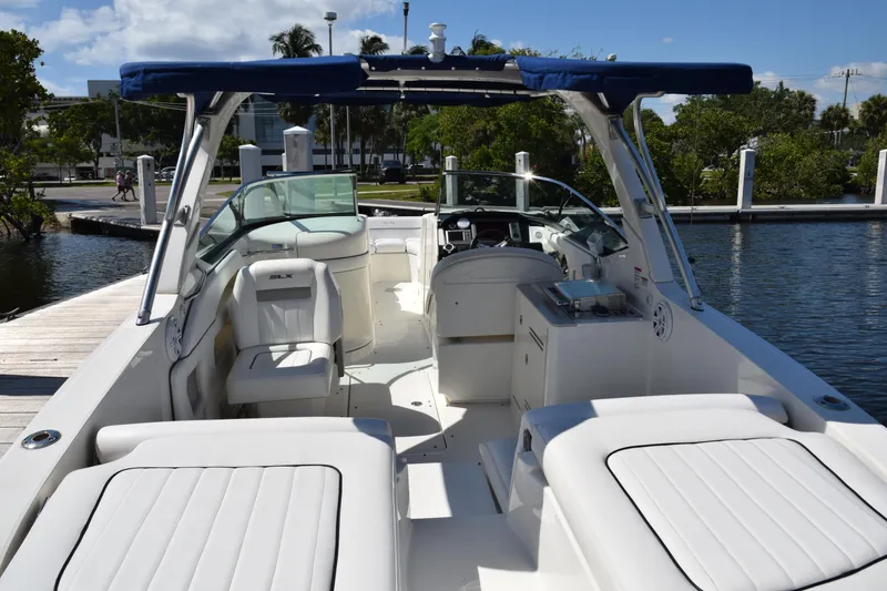 Slide: The Image of 2009 Sea Ray 300 SLX boat with white interior, docked by a scenic waterfront. - 13