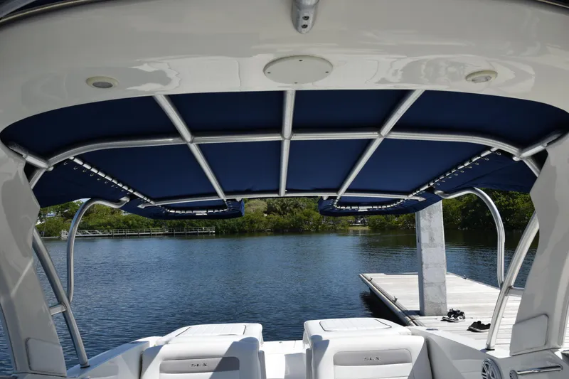 Slide: The Image of 2009 Sea Ray 300 SLX boat with blue canopy, docked by a serene lake. - 25