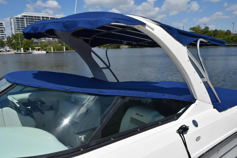 Slide: The Image of 2009 Sea Ray 300 SLX boat with blue canopy on a sunny day by the water. - 44