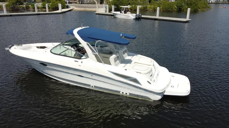 Slide: The Image of 2009 Sea Ray 300 SLX boat with blue canopy on calm water near docks. - 9