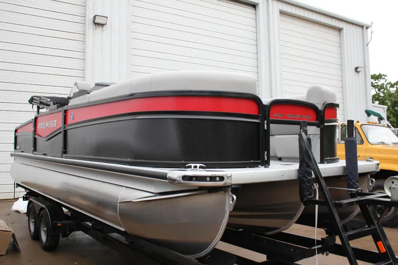 Slide: The Image of 2024 Premier 230 SunSation Angler pontoon boat on trailer outside warehouse. - 12