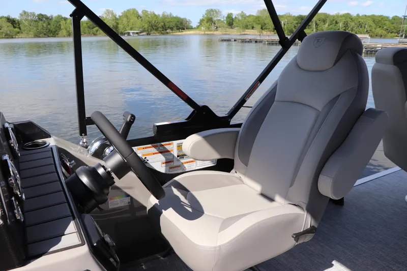 Slide: The Image of Captain's seat on 2024 Premier 230 SunSation Angler boat, overlooking serene lake view. - 21