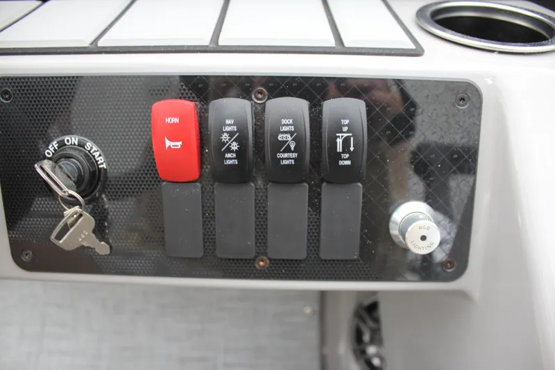 Slide: The Image of Control panel of 2024 Premier 230 SunSation Angler with switches and ignition key. - 27