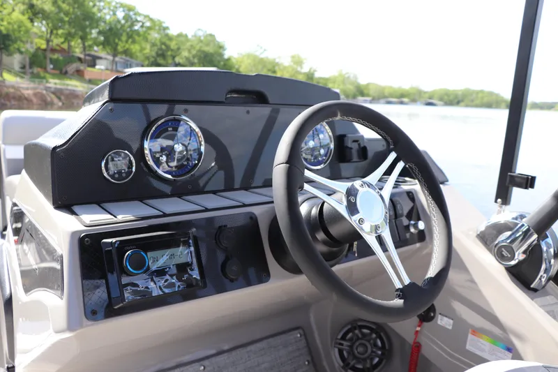 Slide: The Image of 2024 Premier 230 SunSation Angler dashboard with steering wheel and gauges, on a lake. - 5