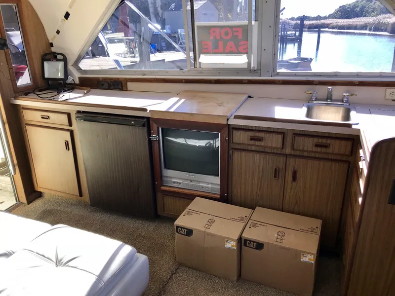 Slide: The Image of Interior of 1981 Bertram 35 Convertible yacht with kitchenette and For Sale sign. - 8
