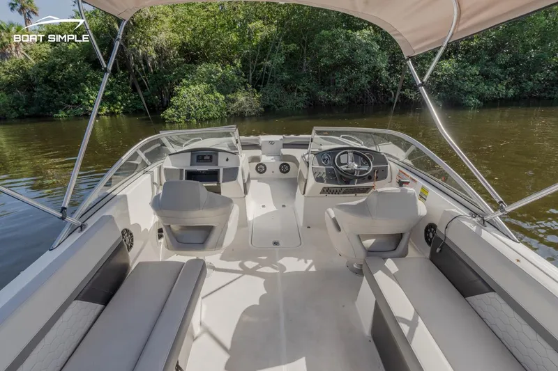 Slide: The Image of 2022 Hurricane 217 SD boat interior with seating and steering wheel on a calm river. - 6