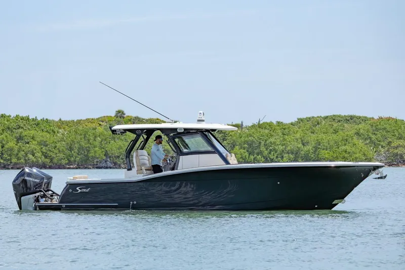 Slide: The Image of 2022 Scout 330 LXF boat cruising on calm water near lush greenery. - 1