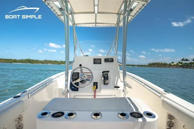 Slide: The Image of 2021 Cobia 201 Center Console boat on water, clear sky, and lush shoreline. - 7