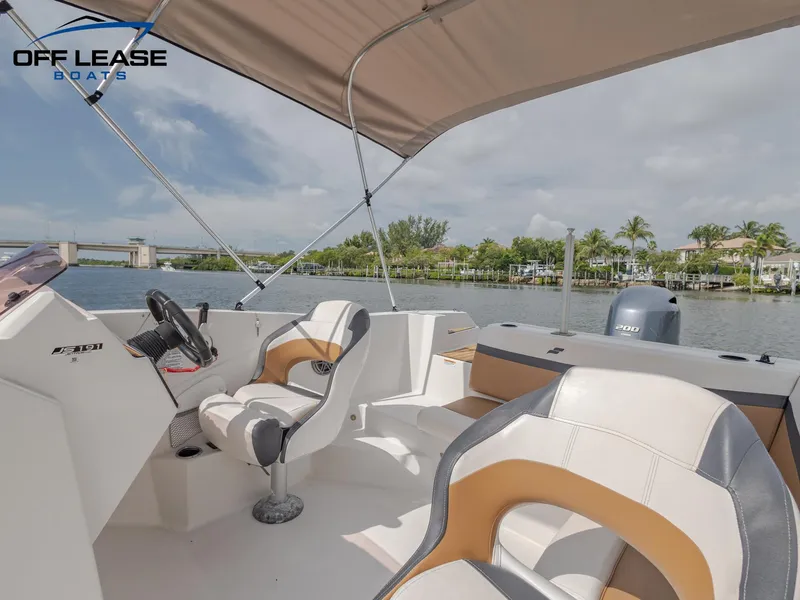 Slide: The Image of 2021 Starcraft SVX 231 OB boat interior with seating and helm, docked by a scenic waterfront. - 10