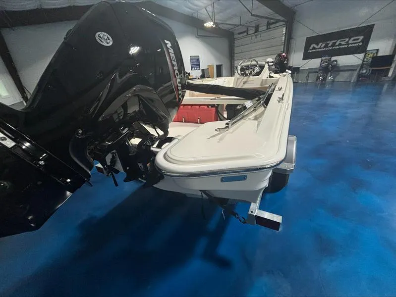 Slide: The Image of 2025 Boston Whaler 160 Super Sport boat in showroom, featuring powerful Mercury engine. - 8