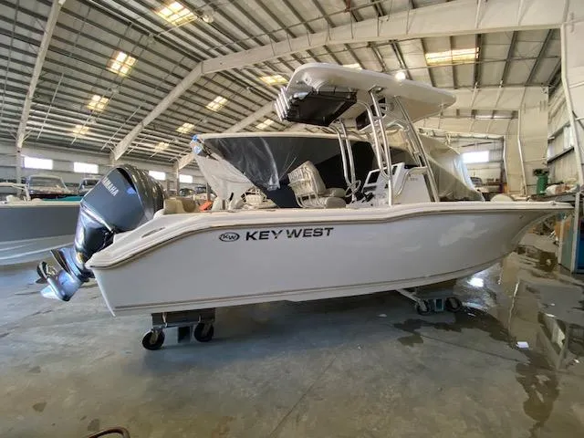 The Image of 2024 Key West 239 FS boat in a warehouse, side view with outboard motor. - 0