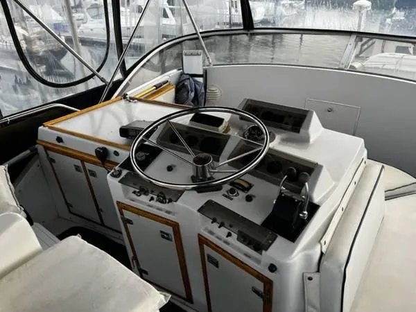 Slide: The Image of 1982 Uniflite Sport Fisher helm with steering wheel and control panels, docked at marina. - 6