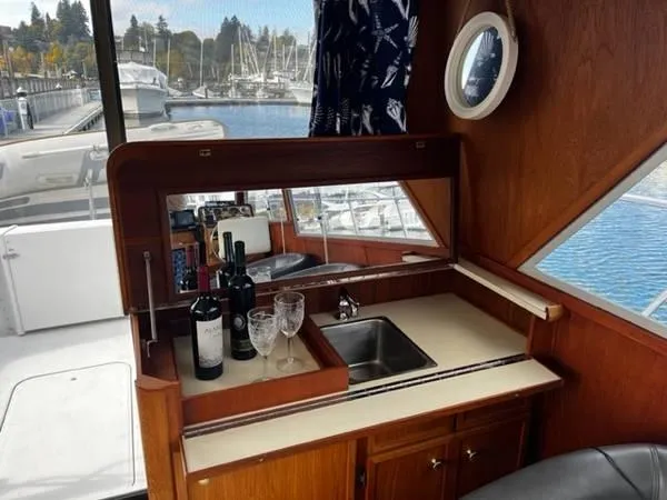 Slide: The Image of 1982 Uniflite Sport Fisher interior with sink, wine bottles, and glasses near marina. - 8