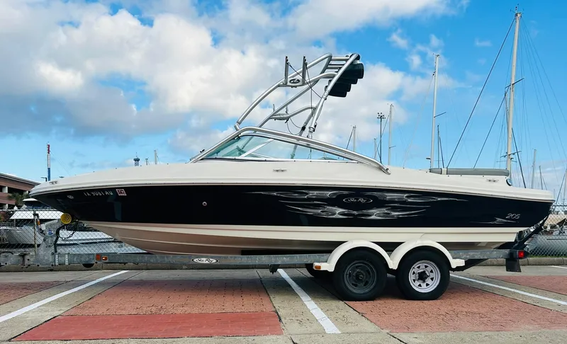 Slide: The Image of 2008 Sea Ray 205 Sport boat on trailer, parked at marina with blue sky background. - 1