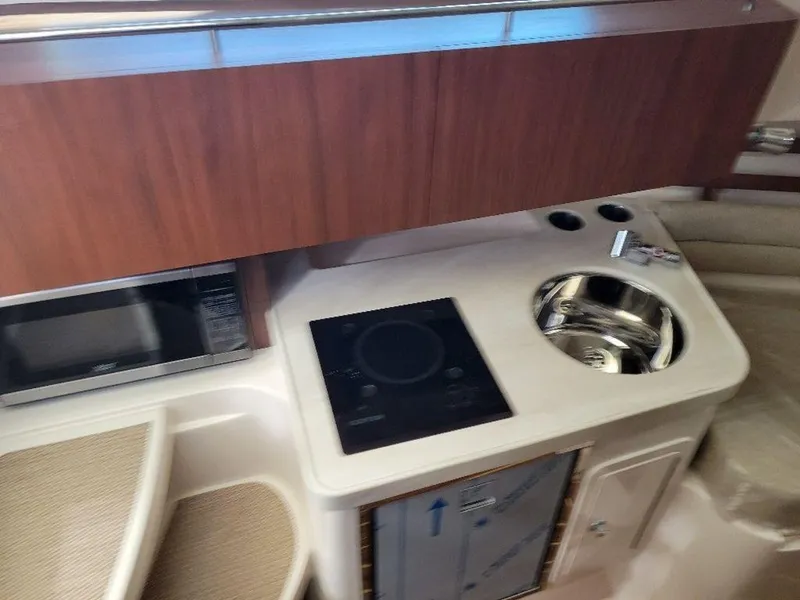 Slide: The Image of 2024 Grady-White Marlin 300 boat interior kitchen with stove, sink, and microwave. - 15