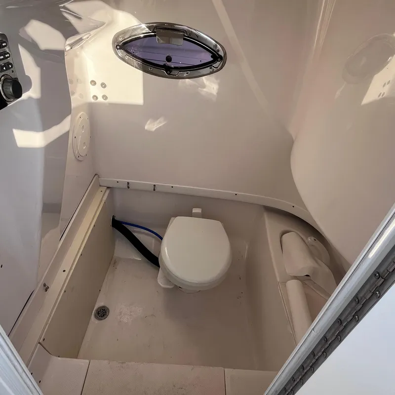 Slide: The Image of 2013 Robalo R240 Center Console boat interior with toilet and porthole. - 15