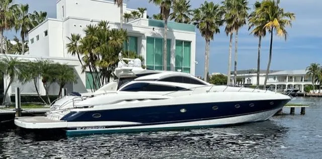 The Image of Sunseeker 75 Predator 2002 yacht docked near modern waterfront home with palm trees. - 0