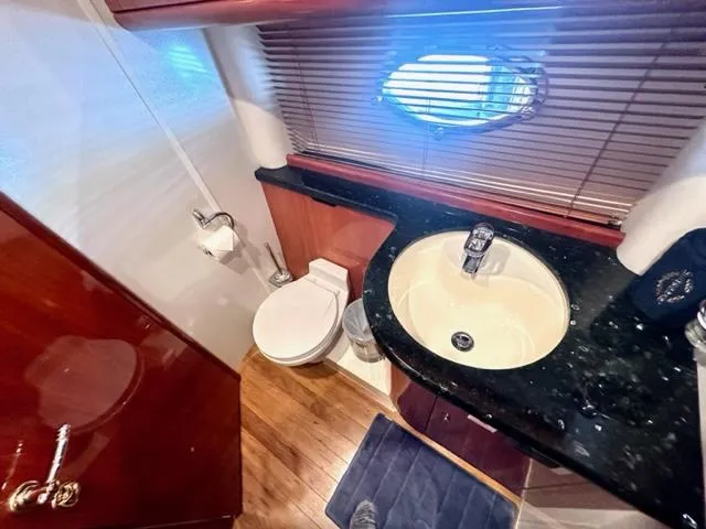 Slide: The Image of Sunseeker 75 Predator 2002 yacht bathroom with sink, toilet, and porthole window. - 17