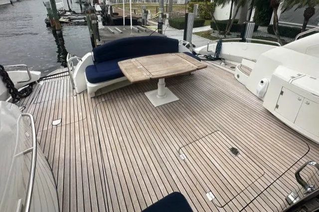Slide: The Image of Sunseeker 75 Predator 2002 yacht deck with wooden flooring, blue seating, and a wooden table. - 2