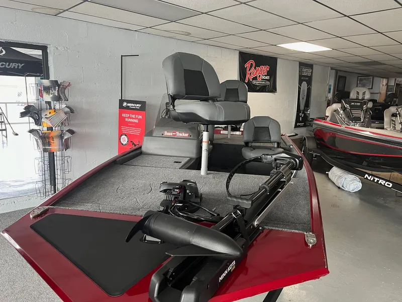 Slide: The Image of 2024 Tracker Bass Tracker Classic XL boat in showroom, featuring red deck and seating. - 2