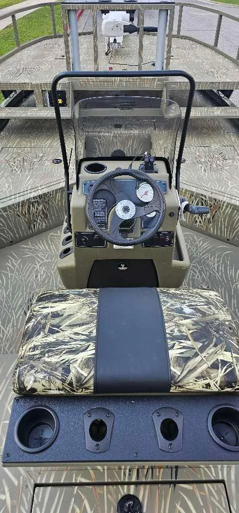 Slide: The Image of 2024 Tracker Grizzly 2072 CC Sportsman boat interior with camo seating and steering console. - 3
