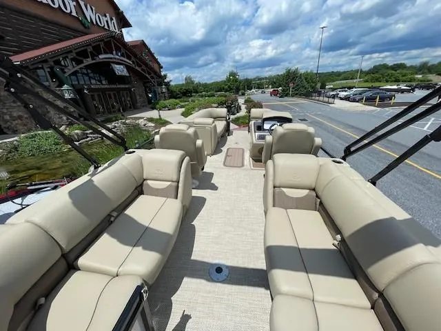 Slide: The Image of 2024 Regency 230 DL3 pontoon boat with beige seating at a dealership. - 5