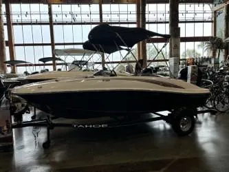 The Image of 2024 Tahoe T16 boat displayed indoors with canopy and trailer. - 0