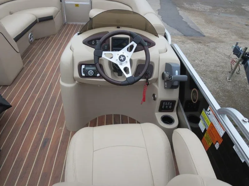 Slide: The Image of Captain's helm of 2015 Berkshire 230CL STS pontoon boat with beige seating and wood flooring. - 4