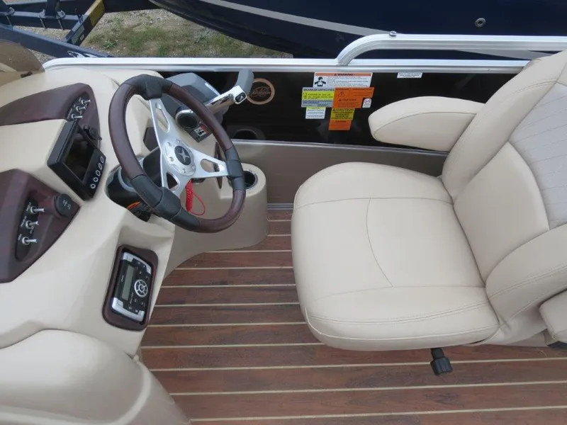 Slide: The Image of Steering console and seat of 2015 Berkshire 230CL STS boat, featuring beige upholstery and wood accents. - 5