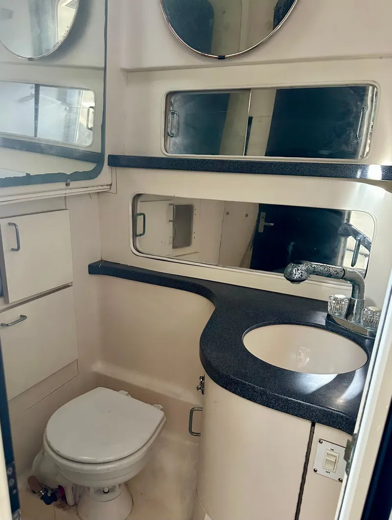 Slide: The Image of 2000 Luhrs Tournament 320 Open bathroom with sink, toilet, and storage cabinets. - 28