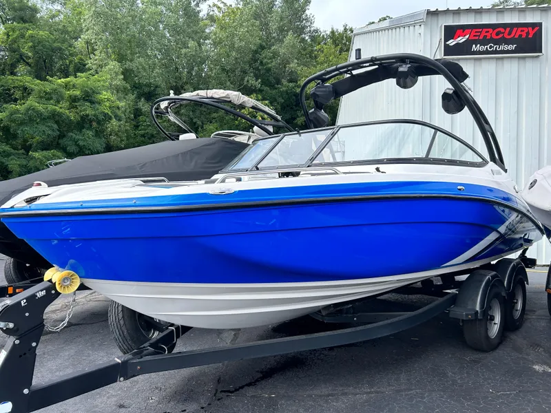 Slide: The Image of 2019 Yamaha Boats AR 210 in blue, parked on a trailer near a Mercury MerCruiser sign. - 14