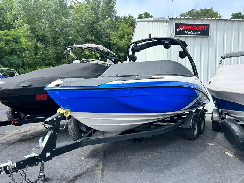 Slide: The Image of 2019 Yamaha Boats AR 210 in blue on a trailer, parked outdoors. - 2
