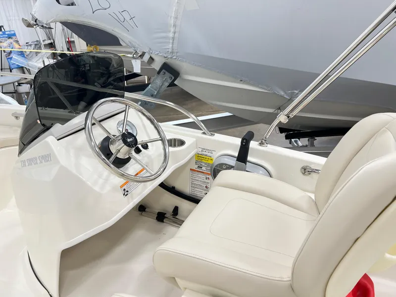 Slide: The Image of 2024 Boston Whaler 130 SPT boat interior with steering wheel and white seating. - 4