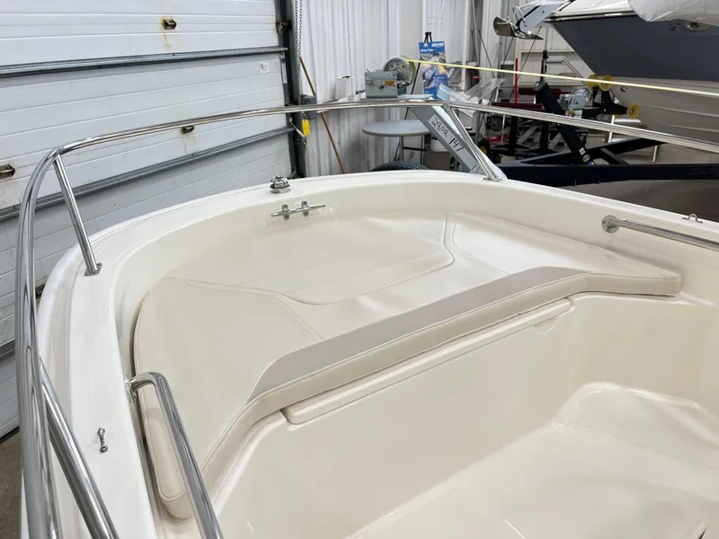 Slide: The Image of 2024 Boston Whaler 130 SPT boat interior, featuring white seating and stainless steel railings. - 5