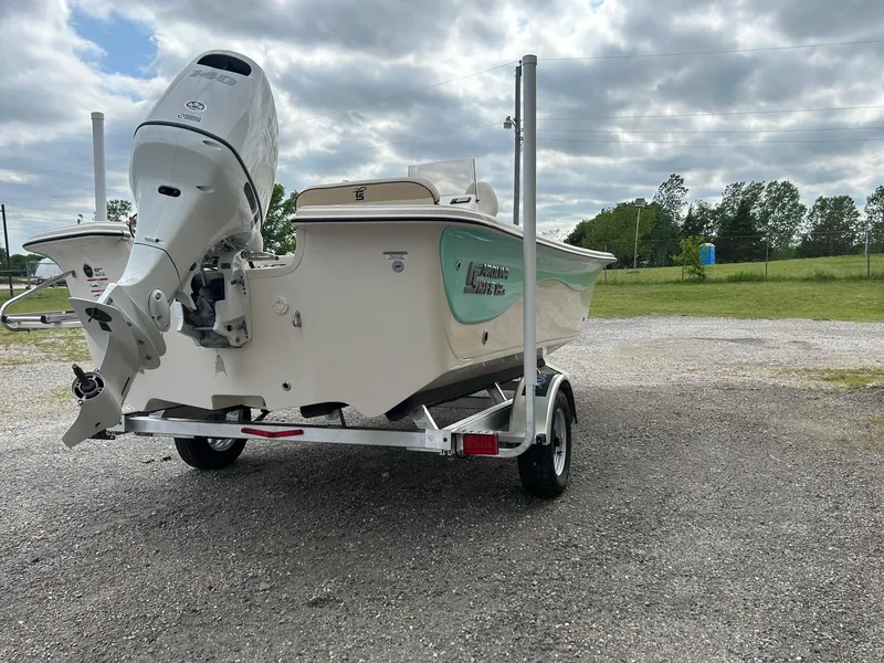 Slide: The Image of 2024 Carolina Skiff 19 LS boat on trailer with outboard motor in a rural setting. - 12