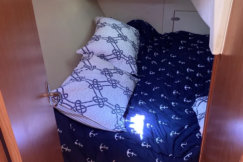 Slide: The Image of Cozy cabin bed in a 2009 Hunter 31-2 sailboat with nautical-themed bedding. - 19