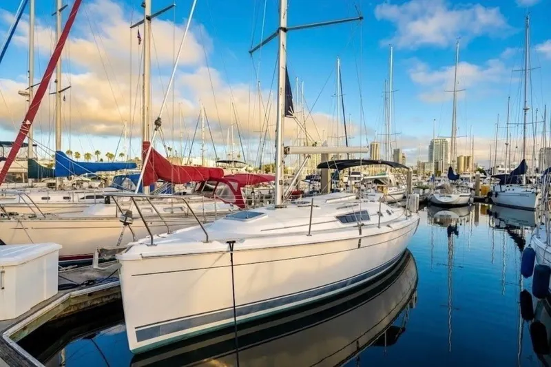 Slide: The Image of 2009 Hunter 31 sailboat docked in a marina, surrounded by other boats under a clear blue sky. - 24