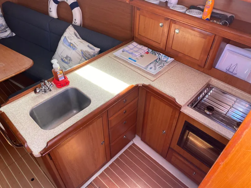 Slide: The Image of 2009 Hunter 31-2 sailboat kitchen with sink, stove, and wooden cabinetry. - 4