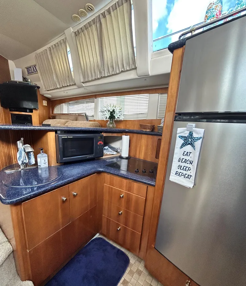 Slide: The Image of 2002 Carver 444 Cockpit Motor Yacht kitchen with microwave, fridge, and countertop. - 18