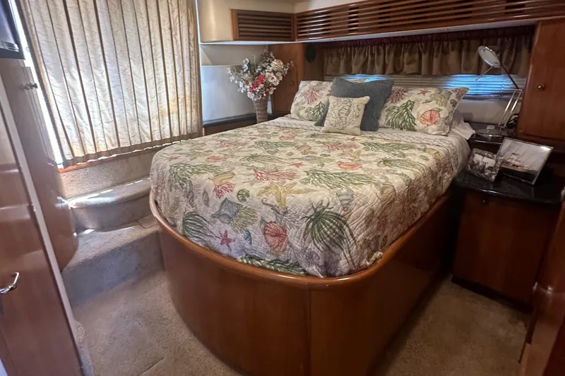 Slide: The Image of 2002 Carver 444 Cockpit Motor Yacht bedroom with floral bedding and wooden cabinetry. - 22