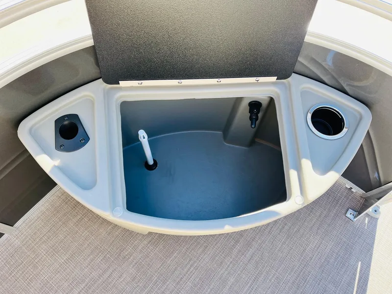 Slide: The Image of Sun Tracker Fishin' Barge 20 DLX 2024 storage compartment with cup holders and rod holders. - 11