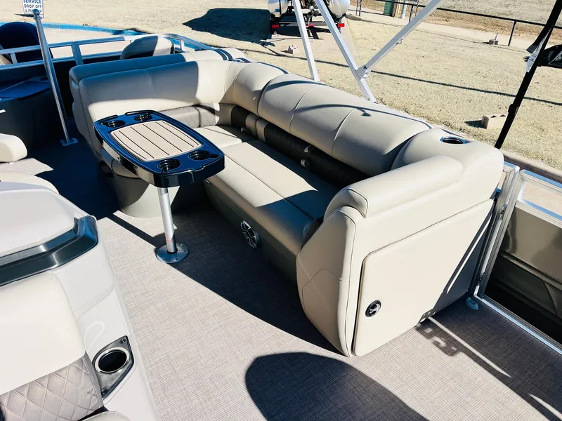 Slide: The Image of 2024 Sun Tracker Fishin' Barge 20 DLX interior with beige seating and table. - 14