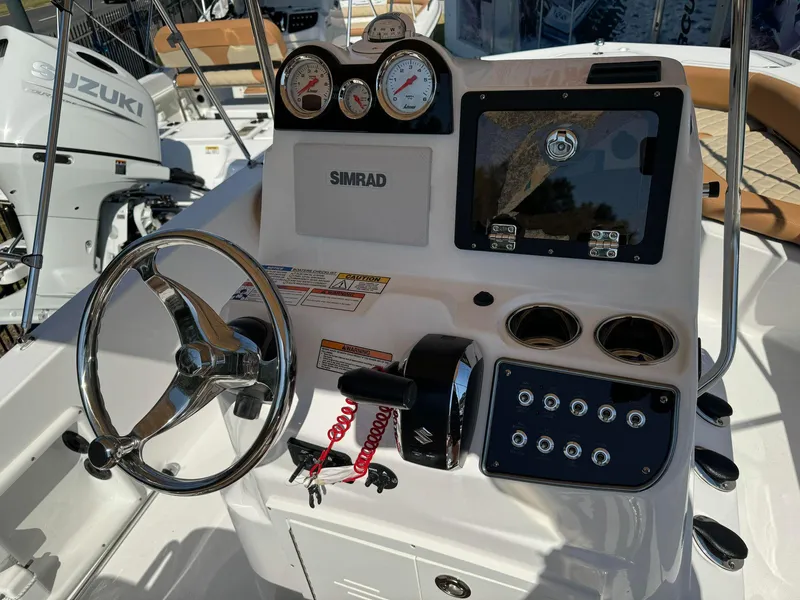 Slide: The Image of 2024 NauticStar 191 Hybrid boat dashboard with steering wheel, gauges, and Simrad display. - 2