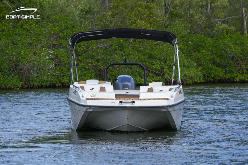 Slide: The Image of 2023 Starcraft SVX 210 OB boat on water with lush green background. - 2