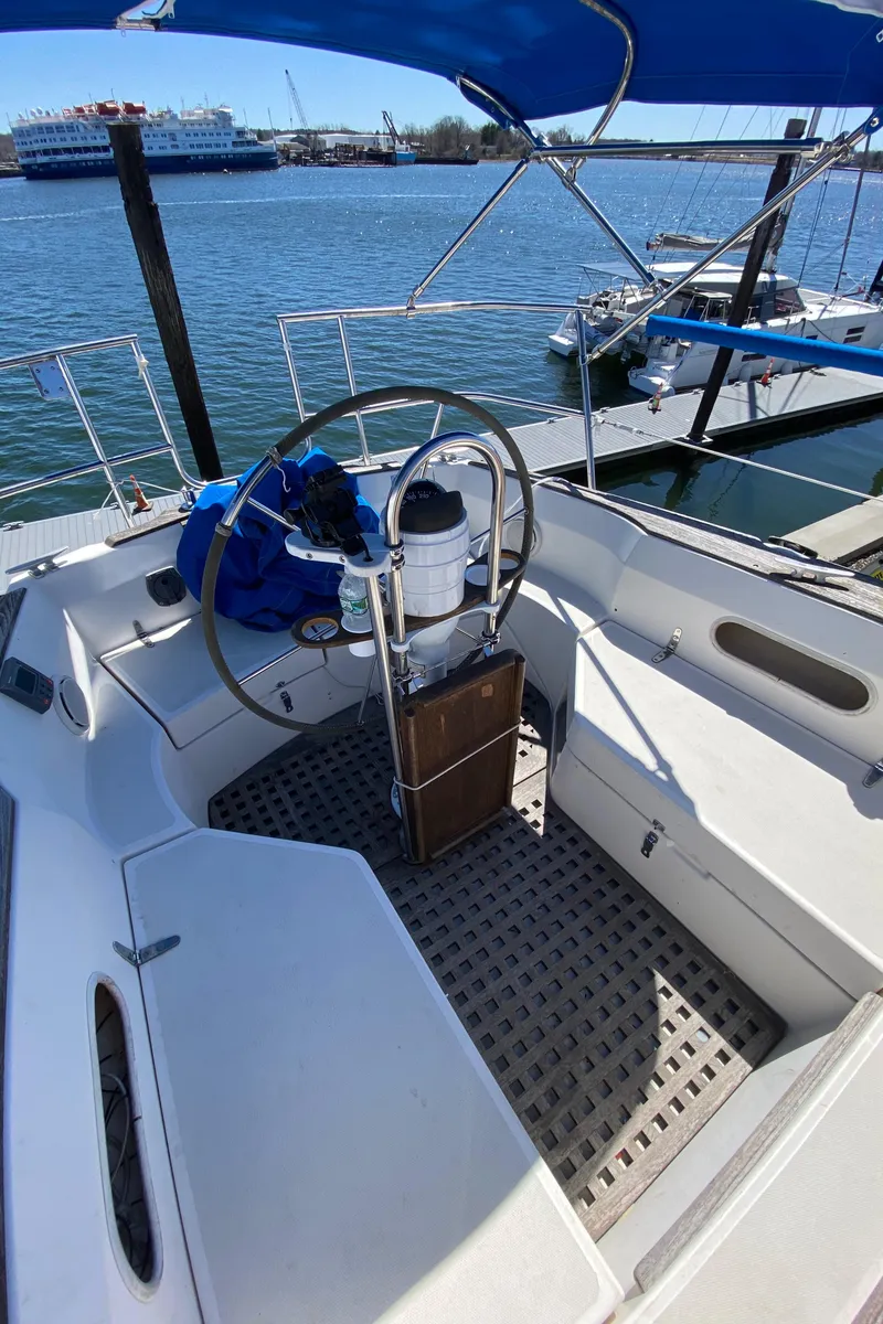 Slide: The Image of 1985 Sabre 32 sailboat cockpit with steering wheel and marina view. - 11