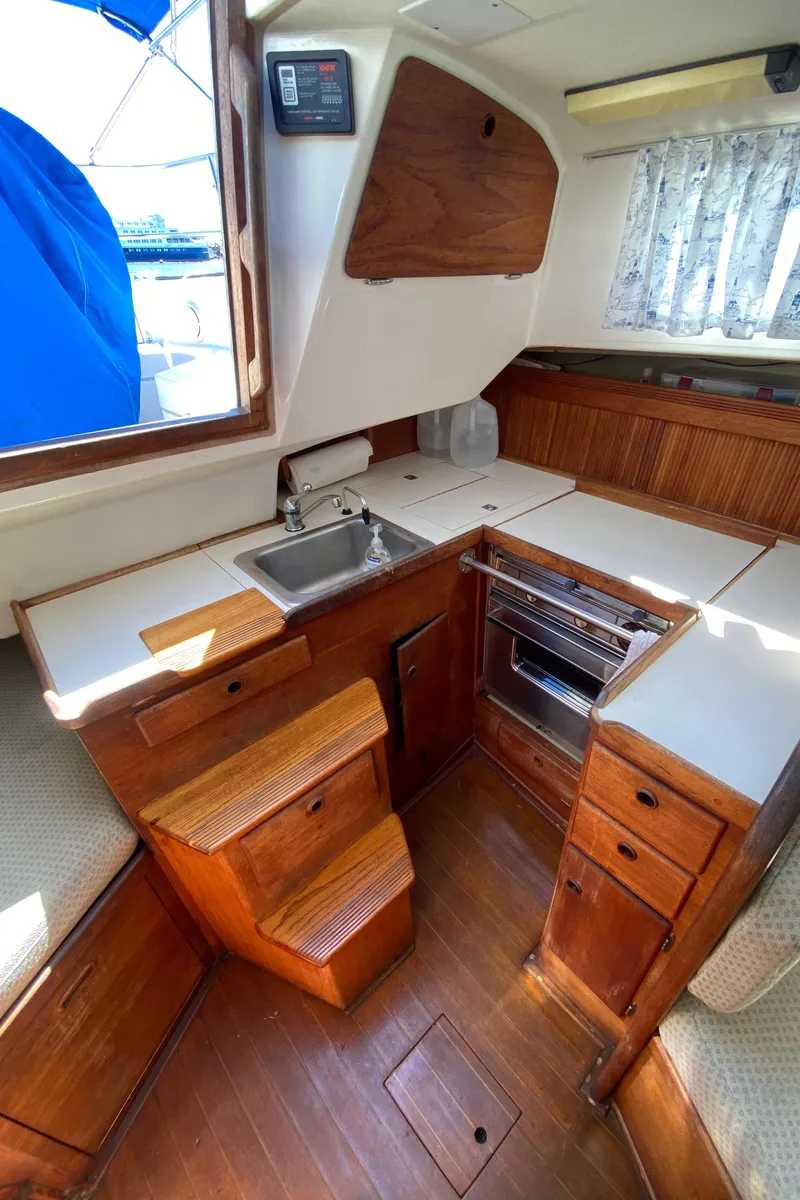 Slide: The Image of 1985 Sabre 32 sailboat galley with wooden cabinetry, sink, and stove. - 17