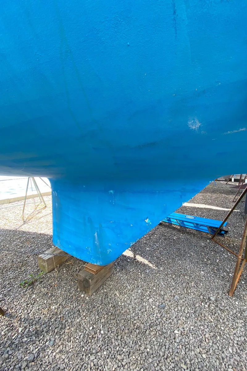 Slide: The Image of Close-up of the hull of a 1985 Sabre 32 sailboat on a gravel surface. - 7