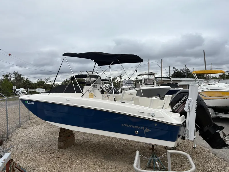 Slide: The Image of 2018 Bayliner F21 boat with blue hull and black canopy, parked on gravel. - 4