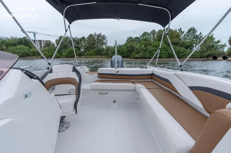 Slide: The Image of 2022 Starcraft SVX 211 OB boat interior with seating and canopy on a calm waterway. - 10
